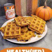 Stack of pumpkin waffles with canned pumpkin puree and some pumpkin decor in the background