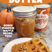 A jar of homemade pumpkin butter, a pumpkin waffle on a white plate with pumpkin butter and pepitas, and pumpkin decor in the background.