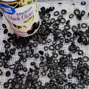 Can of black olives and sliced olives on dehydrator rack for drying