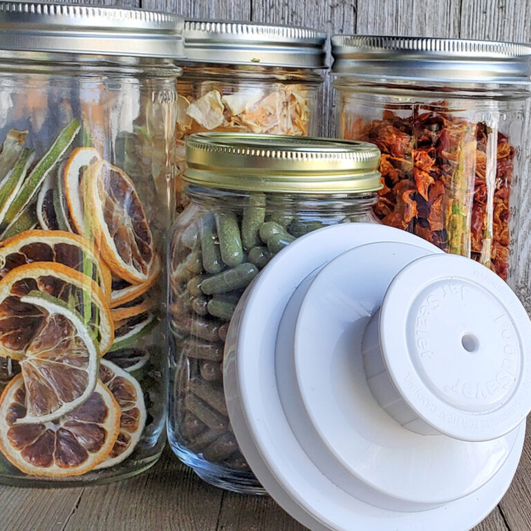 Food saver vacuum sealing attachment in front of jars full of dehydrated fruits and vegetables