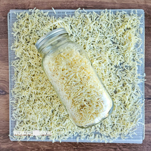 a jar of dehydrated hash browns on a dehydrator tray of dried shredded potatoes