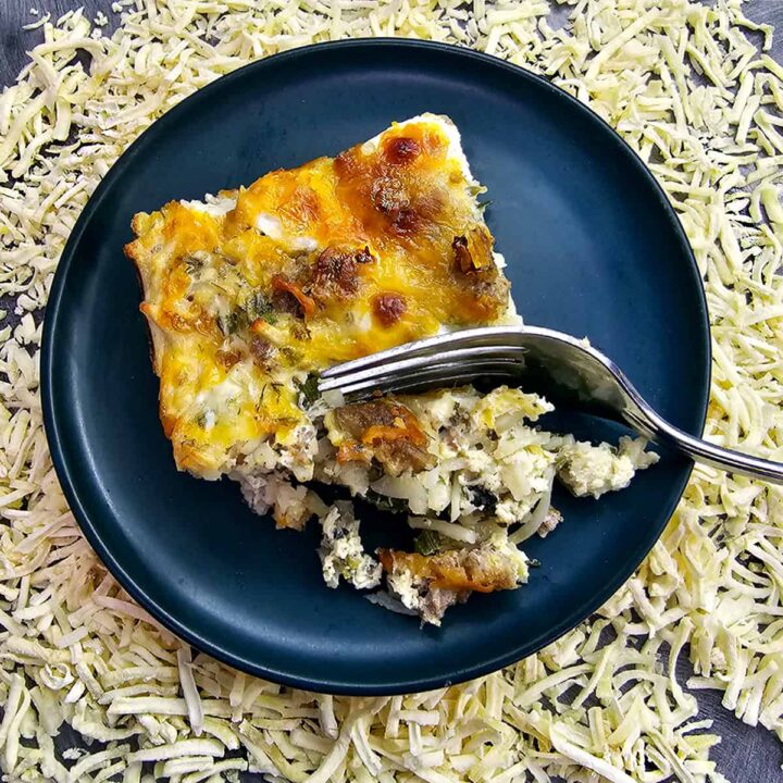 Hashbrown breakfast casserole on blue plate on a bed of dehydrated hash browns.