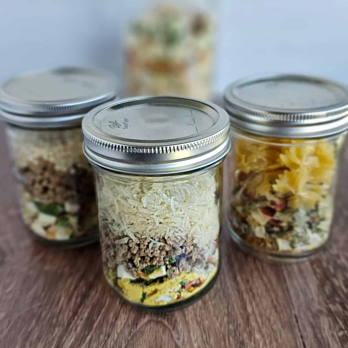 Meals in a jar of instant beef and vegetable soup; one with rice, one with pasta, one with couscous.