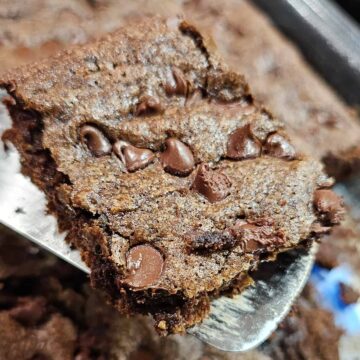 Chocolate Chip Zucchini brownie on a spatula over a dish of brownies.