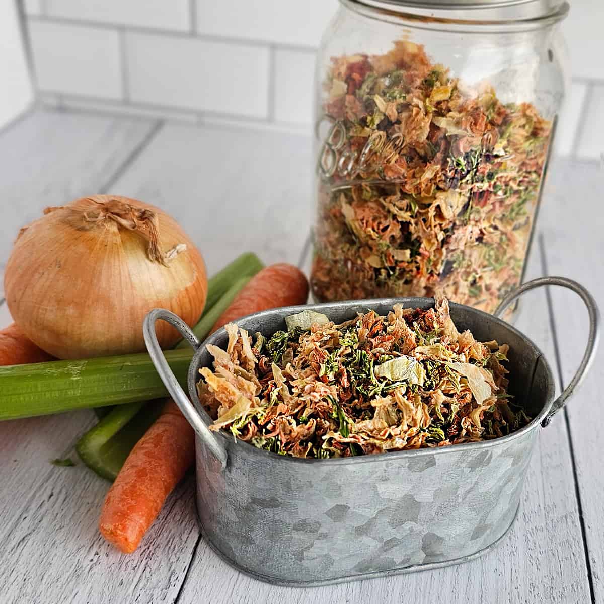 A container of dried mirepoix with carrots and celery next to it.