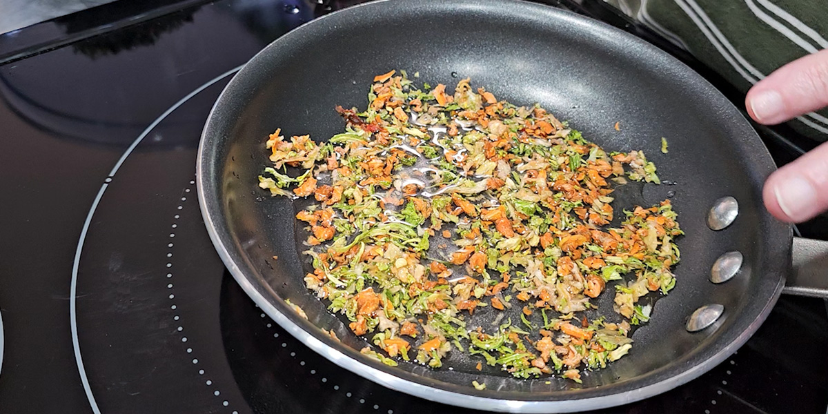 A person is rehydrating vegetables in a frying pan.