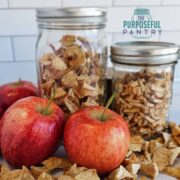 Dried apples in jars with fresh apples and text overlay 'Dehydrated apples to use in baking later.'