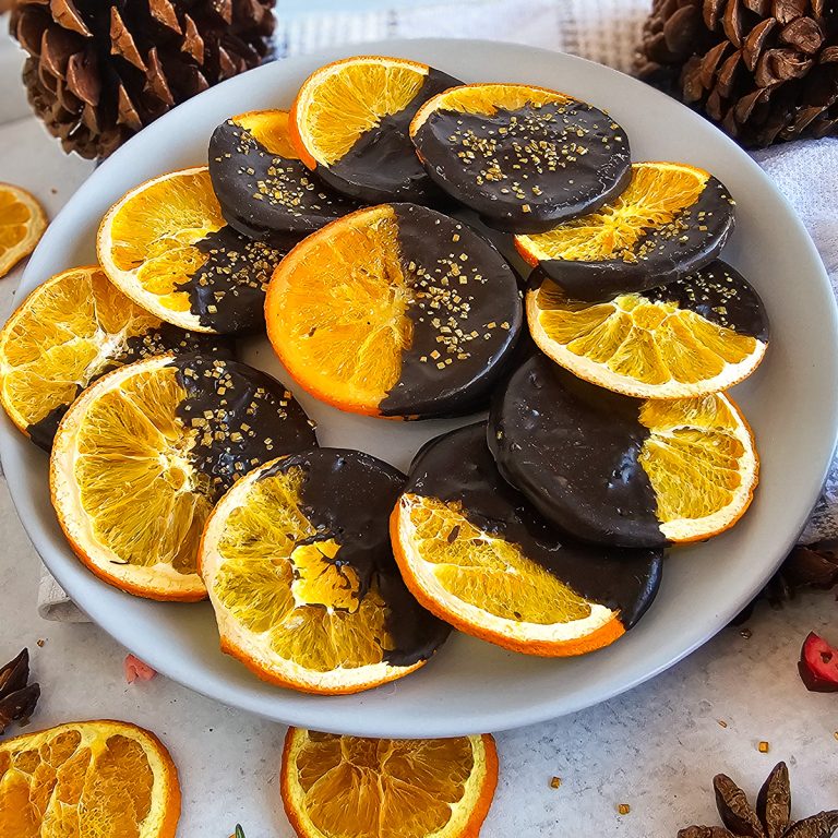 A plate with chocolate covered oranges and pine cones.