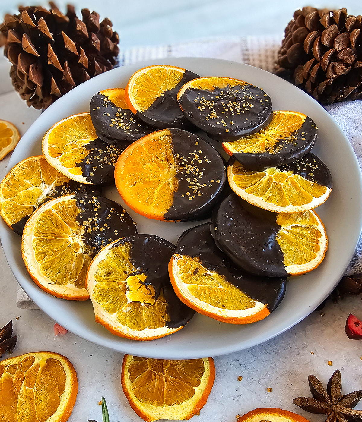 A plate with chocolate covered oranges and pine cones.