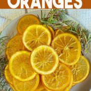 Diy candied oranges on a plate with sprigs of rosemary.