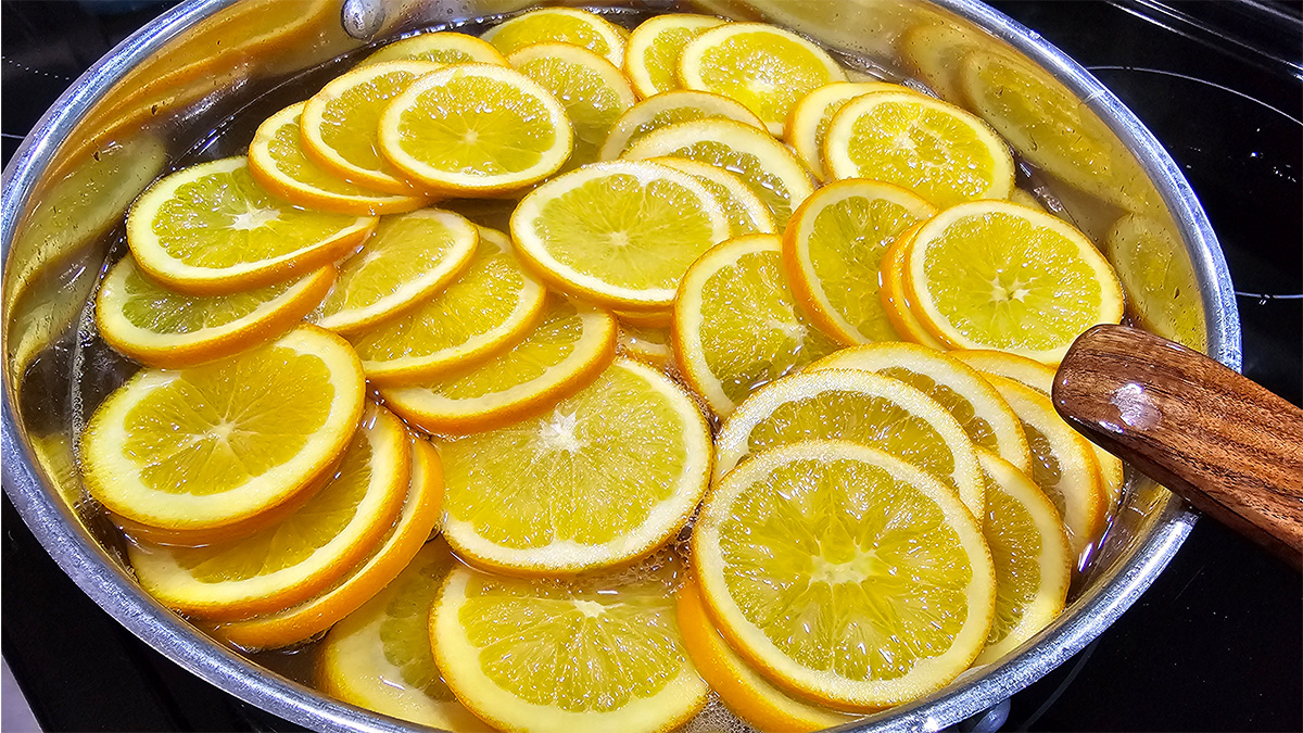 Simmering oranges slices in a simple syrup solution for candied oranges.