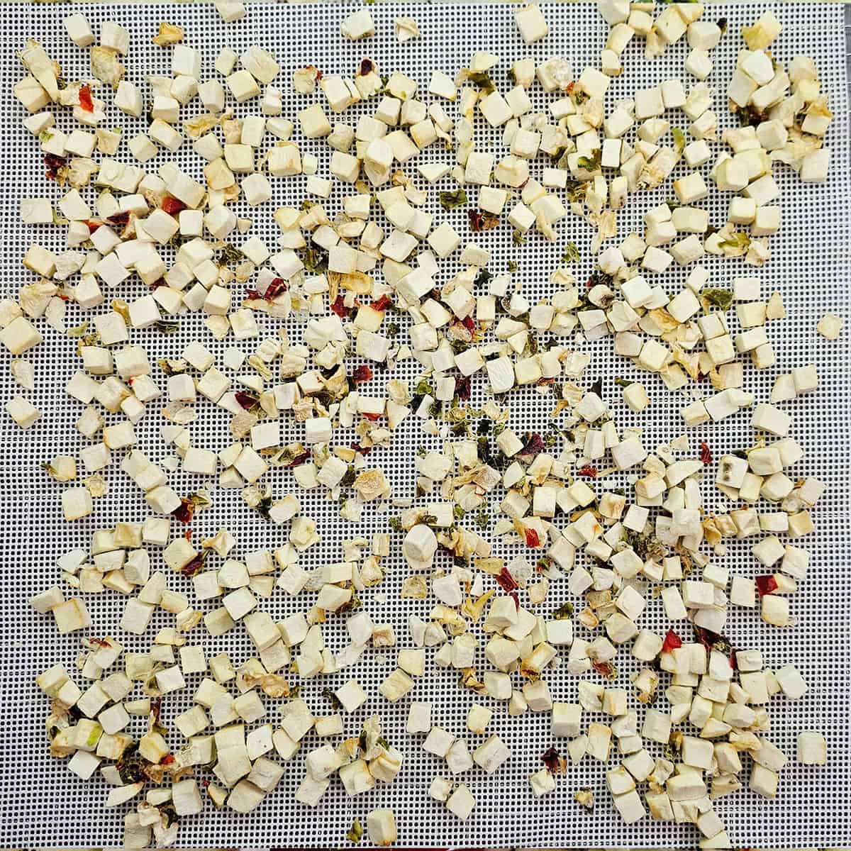 A mesh surface covered with small, evenly scattered, dried Potatoes O'brien from frozen.